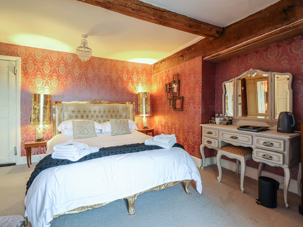 A bedroom with a large bed and dresser at Plas Dolguog in Machynlleth