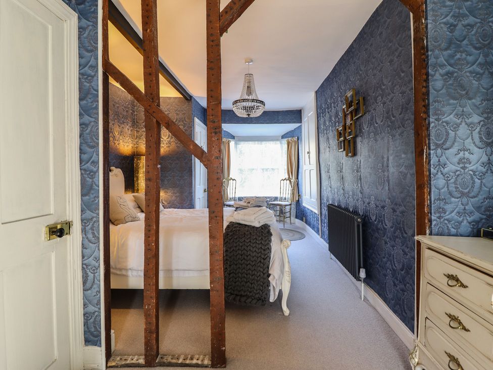 A bedroom with a bed and chandelier at Plas Dolguog Machynlleth