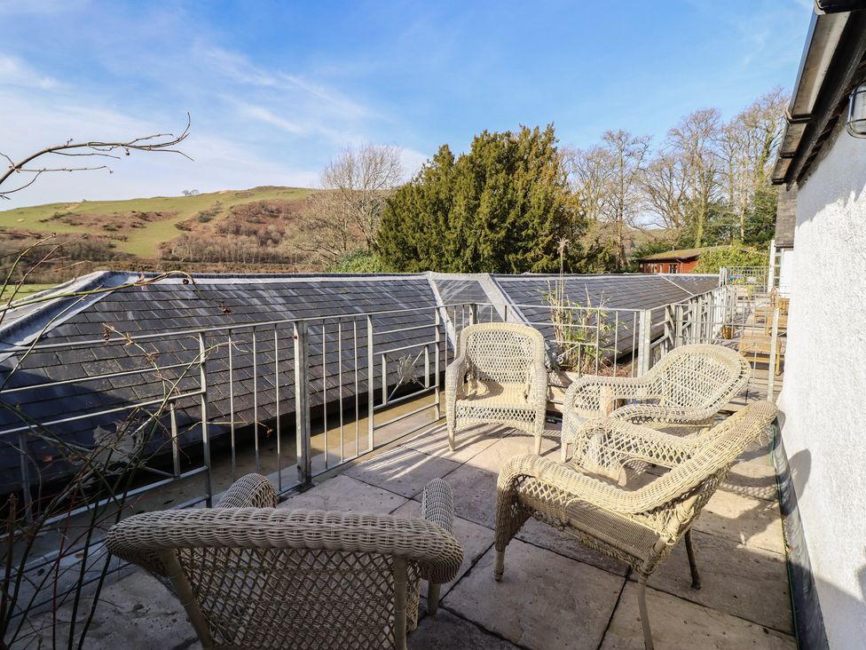 An outdoor area with wicker chairs and a slate roof at Plas Dolguog Machynlleth