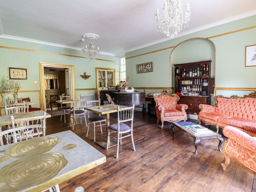 A lounge with tables and seating at Plas Dolguog in Machynlleth
