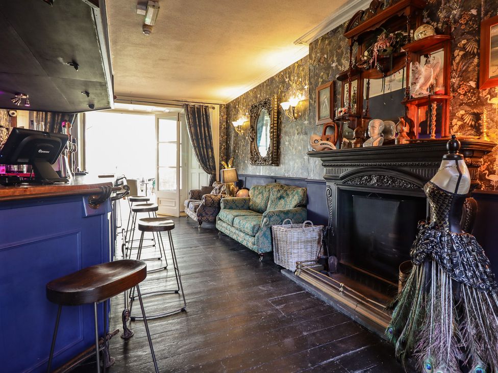A living room with a bar area and a fireplace at Plas Dolguog in Machynlleth
