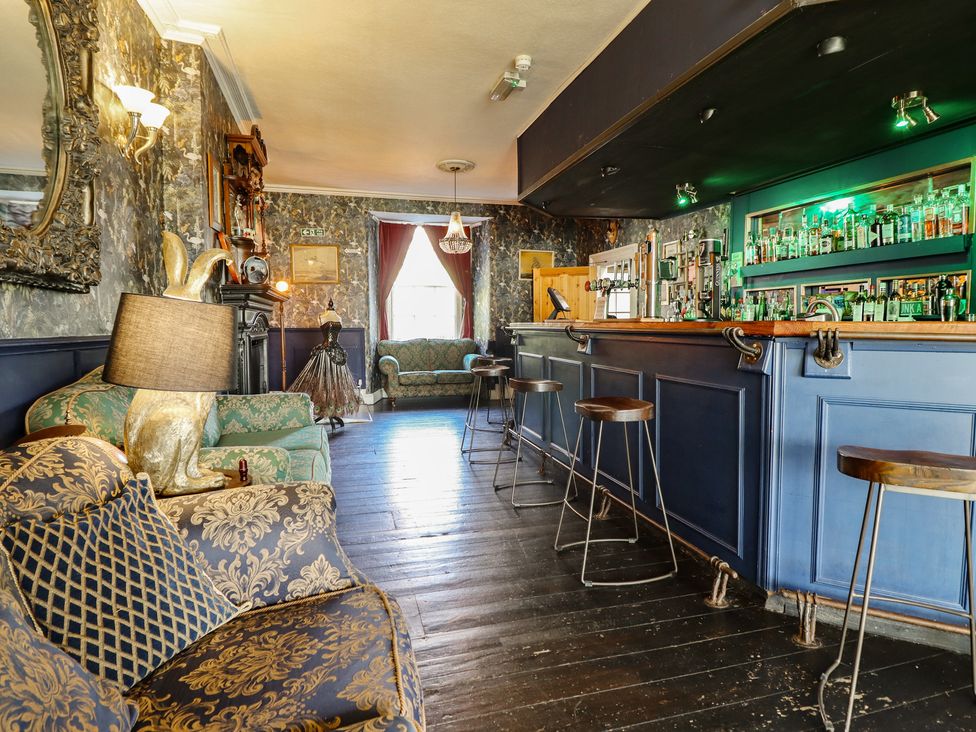 A lounge with a bar and seating area at Plas Dolguog in Machynlleth