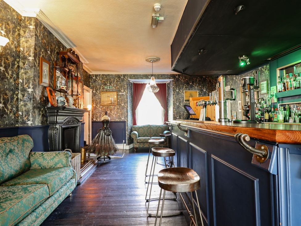 A bar area with a wooden counter and seating at Plas Dolguog Machynlleth