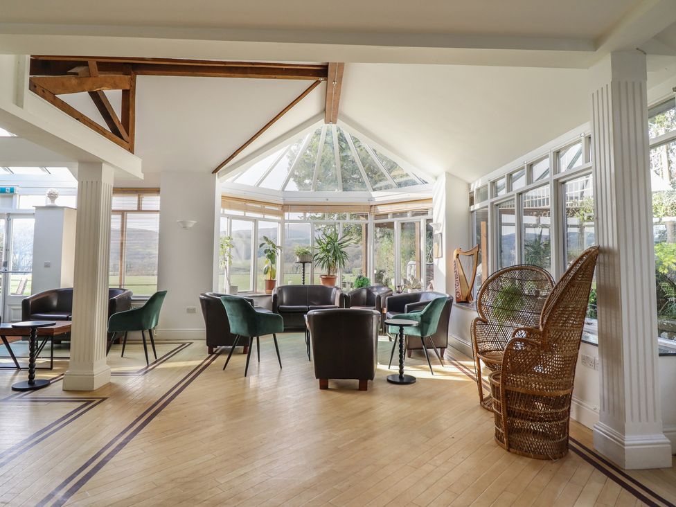 A conservatory with seating and plants at Plas Dolguog in Machynlleth