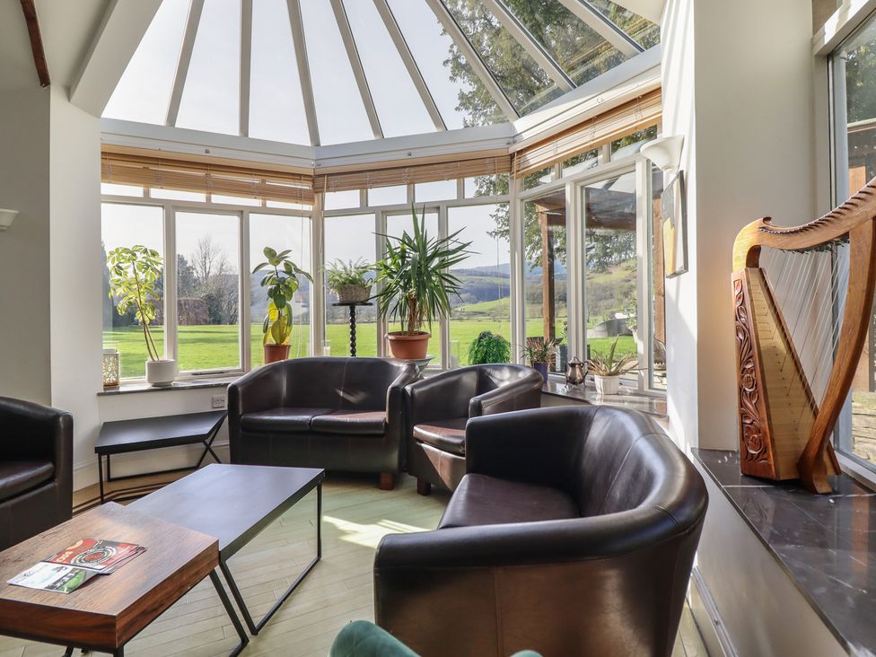 A conservatory with seating area and plants at Plas Dolguog in Machynlleth