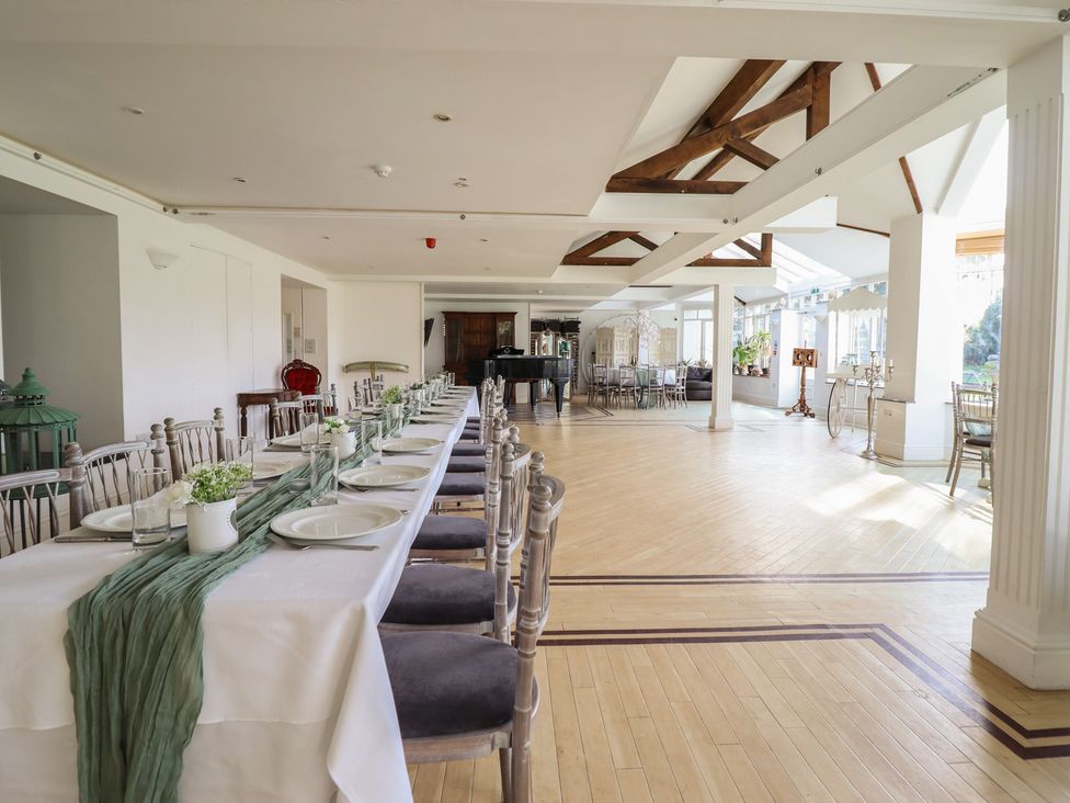 A dining room with a long table and chairs at Plas Dolguog in Machynlleth