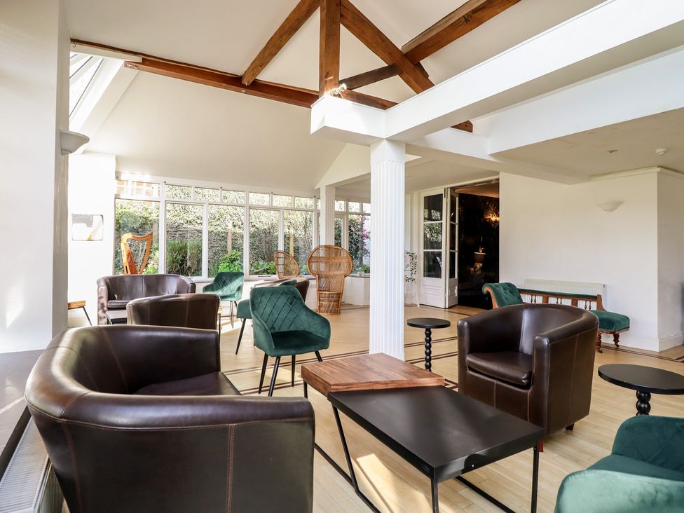 A sunroom with chairs and a coffee table at Plas Dolguog in Machynlleth