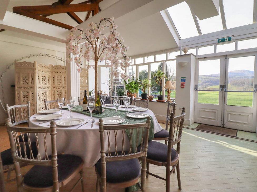 A dining room with a large table and chairs at Plas Dolguog in Machynlleth