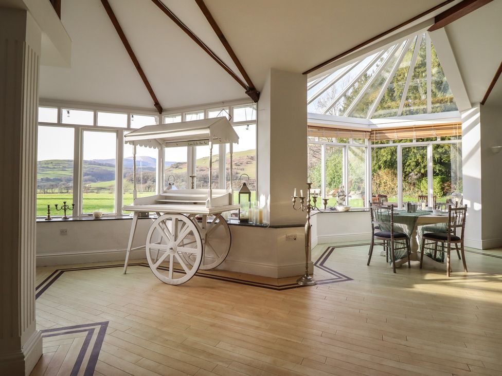 A conservatory with a cart and table at Plas Dolguog in Machynlleth