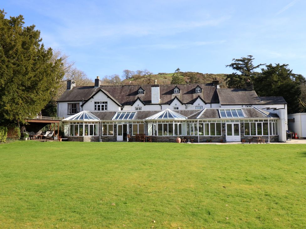 A house with a conservatory and lawn at Plas Dolguog in Machynlleth