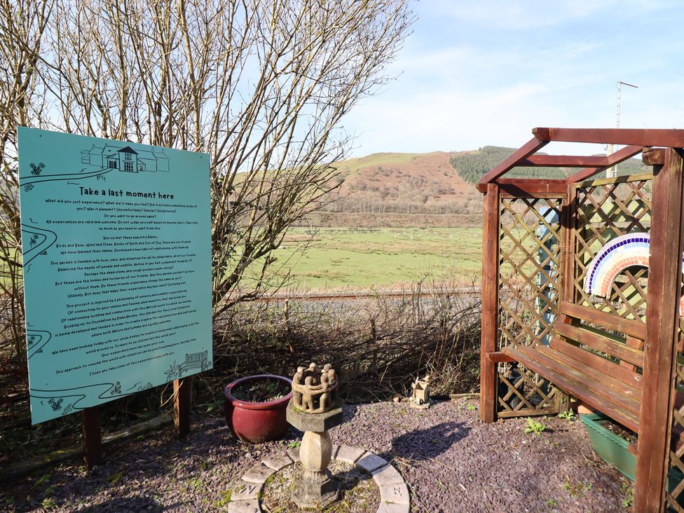 An outdoor area with a sign and a bench at Plas Dolguog in Machynlleth