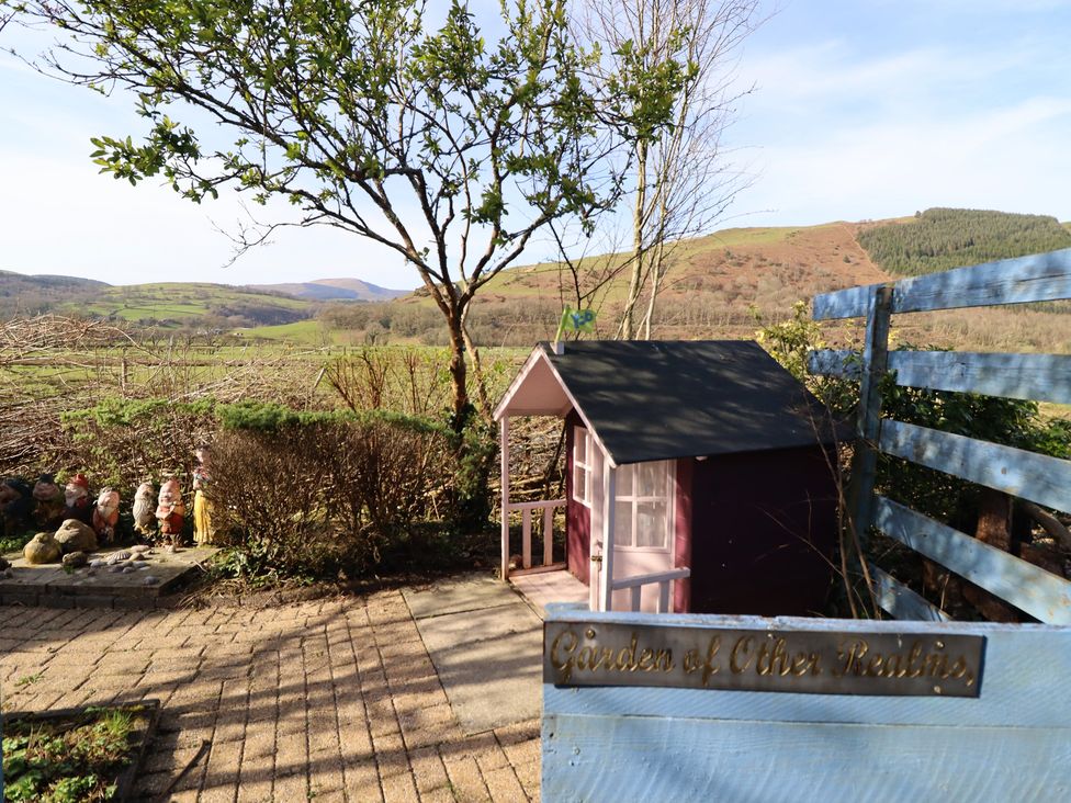 A garden with a playhouse and gnomes at Plas Dolguog in Machynlleth