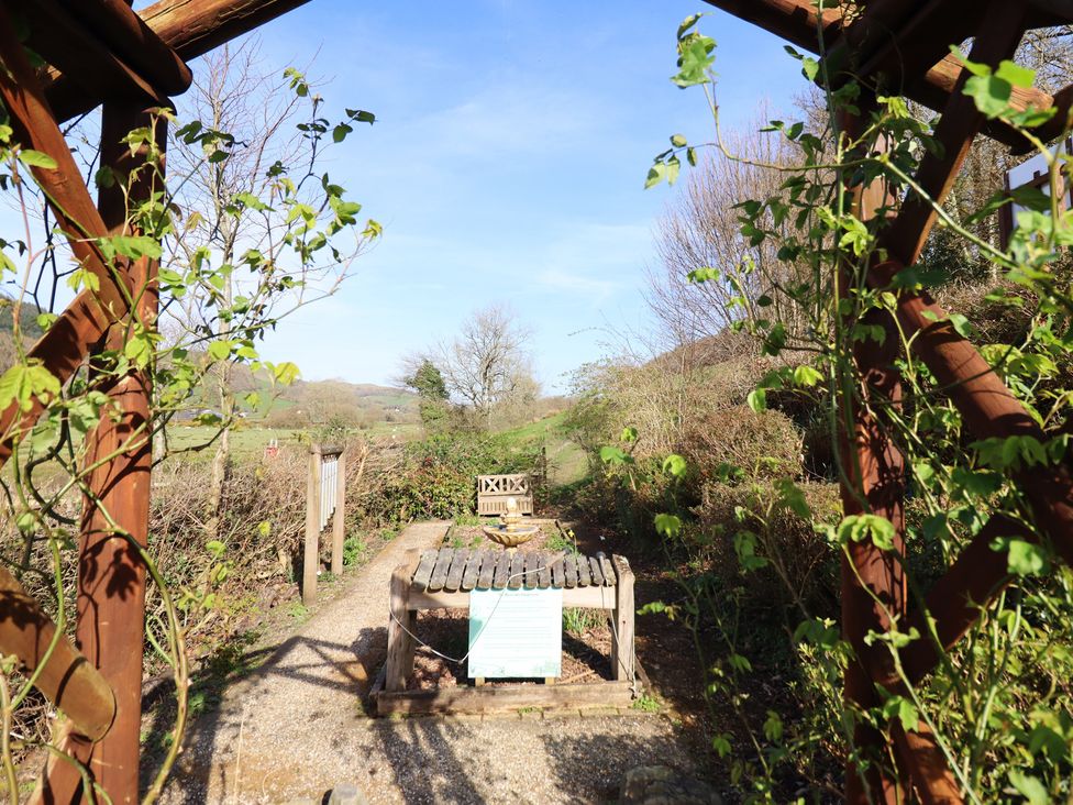 A garden pathway leading to a bench and gazebo at Plas Dolguog in Machynlleth