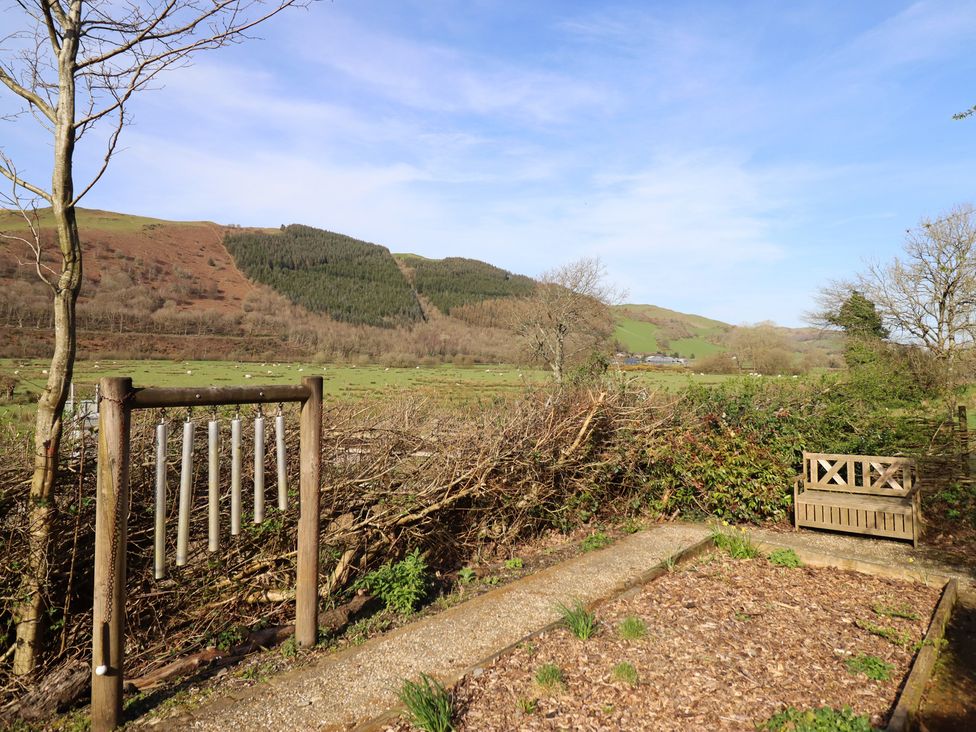 An outdoor area with wind chimes and a bench at Plas Dolguog in Machynlleth