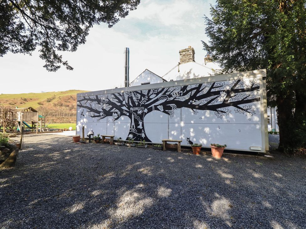 An outdoor area with a tree mural on the wall at Plas Dolguog in Machynlleth