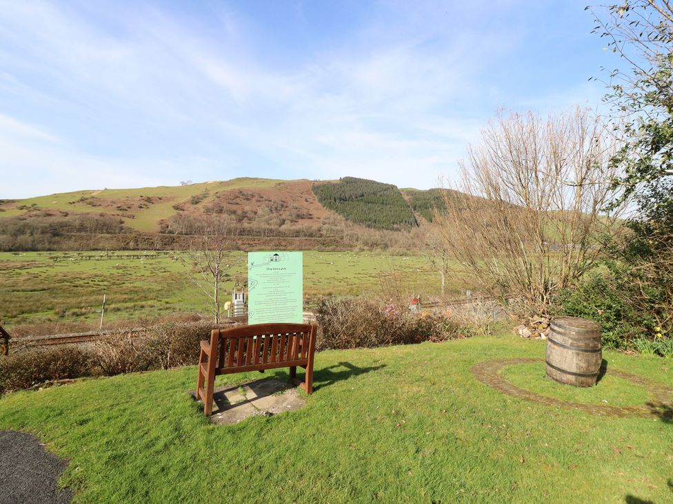 A bench and sign in an outdoor area with hills in the background at Plas Dolguog, Machynlleth