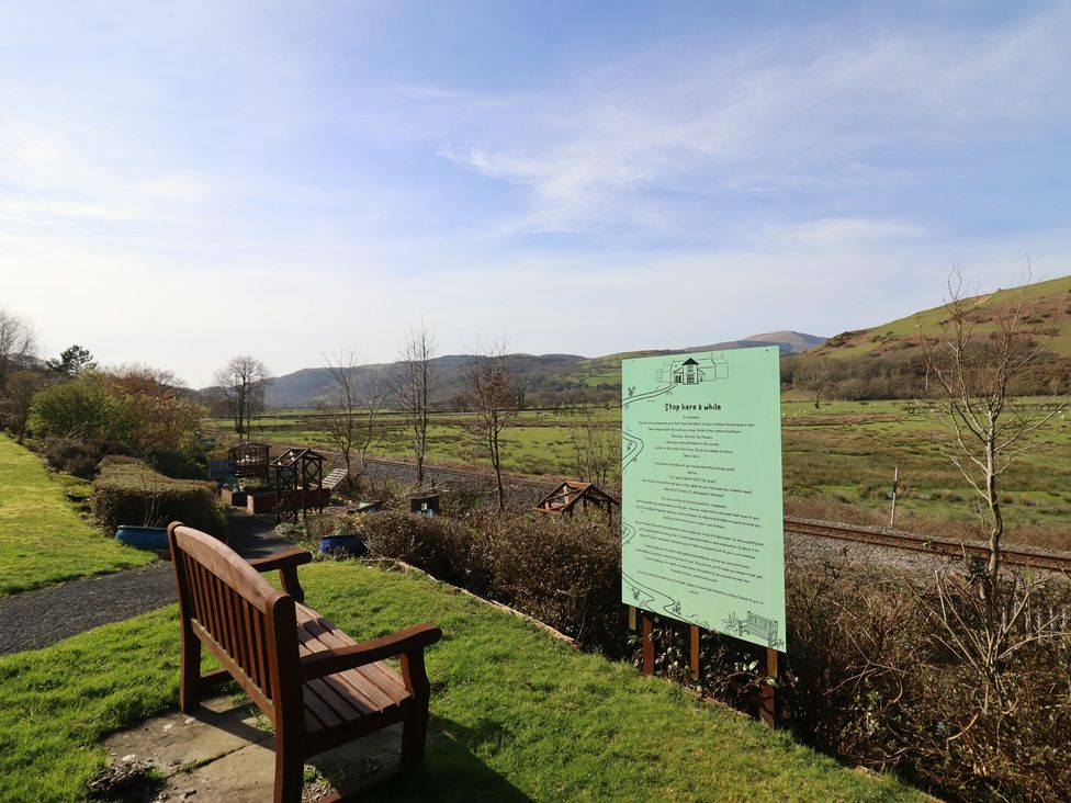 A view with a bench and a sign in a landscape at Plas Dolguog in Machynlleth