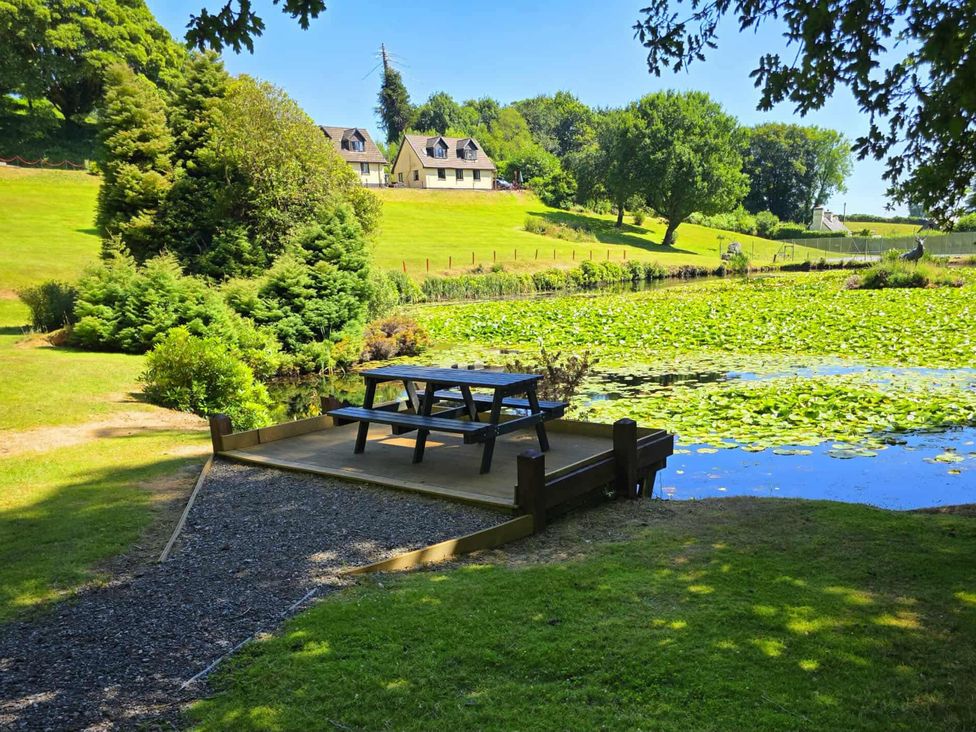 A deck with a picnic table near a pond at Lakeview Villa near Liskeard