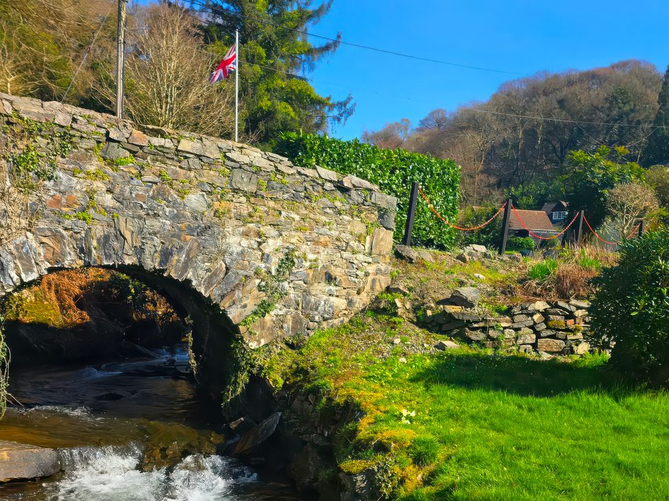 A bridge over water with a flag near trees at Lakeview Villa near Liskeard