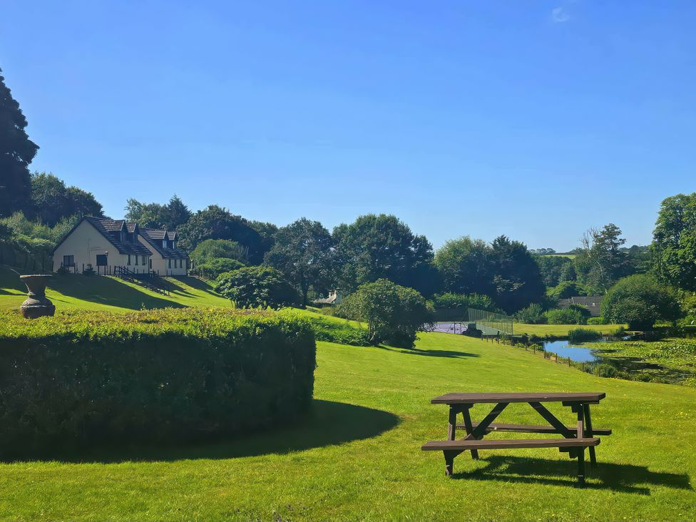 A garden with a picnic table and a pond at Lakeview Villa near Liskeard