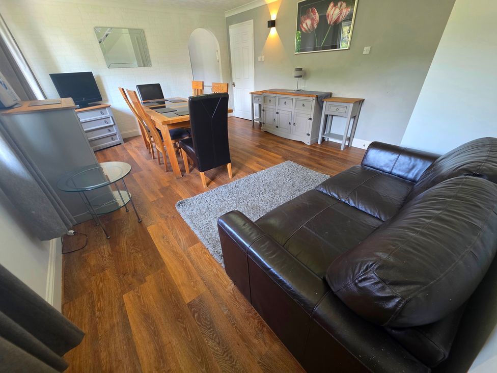 A living room with a sofa and dining area at Lakeview Villa near Liskeard