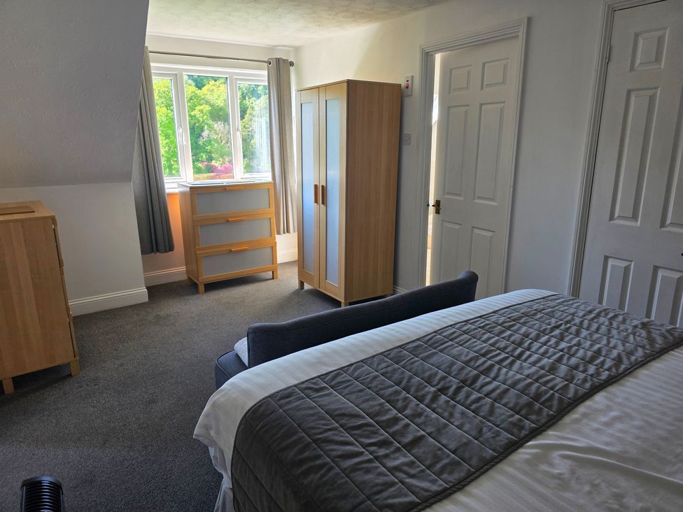 A bedroom featuring a bed, wardrobe, and chest of drawers at Lakeview Villa near Liskeard