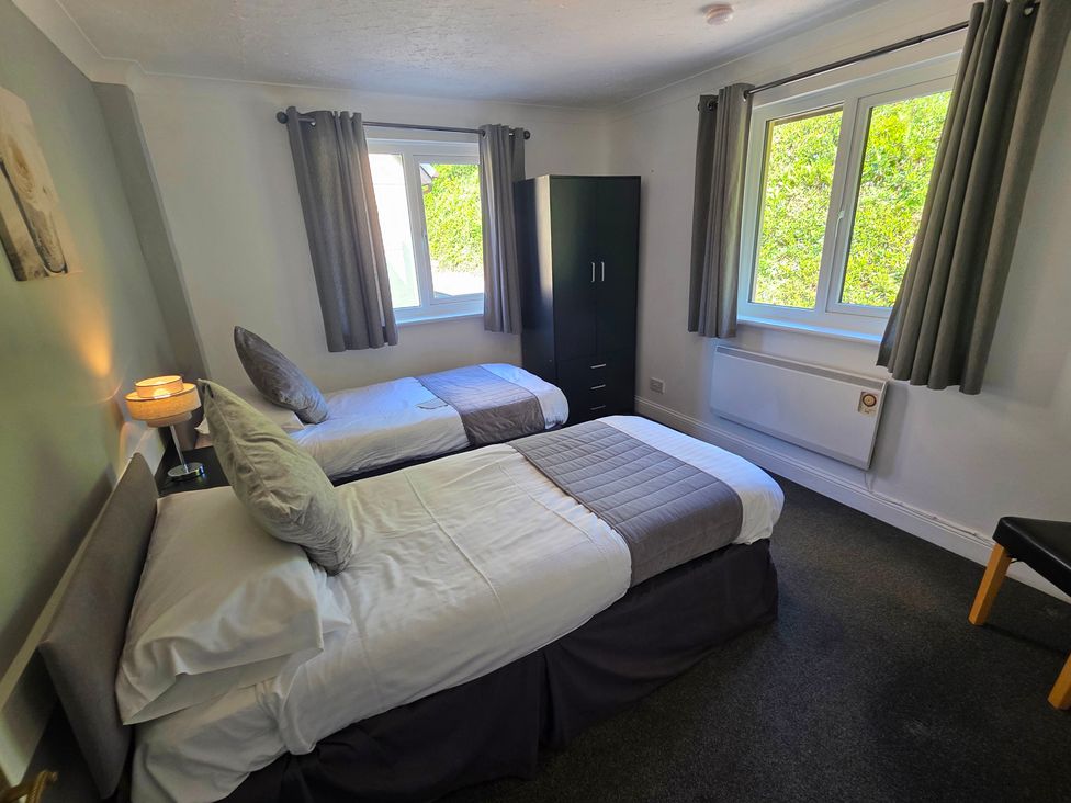 A bedroom with two beds and a wardrobe at Lakeview Villa near Liskeard