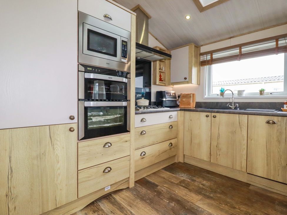 A kitchen with cabinets, oven, microwave, and sink at 8 Summerleaze, Bude