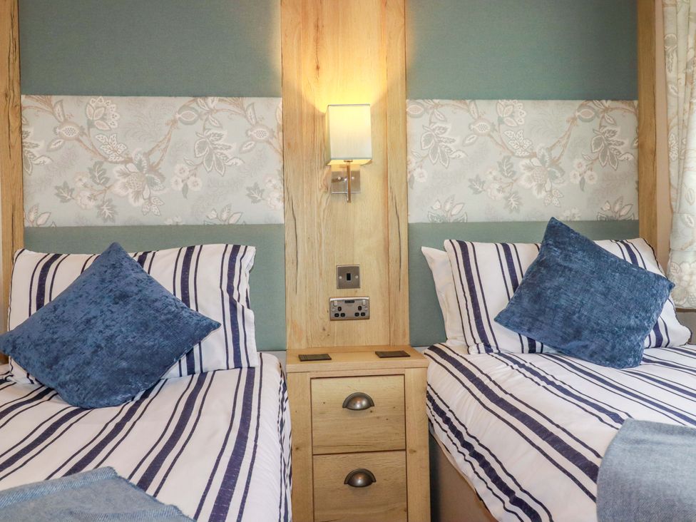 A bedroom with two beds and a bedside table at 8 Summerleaze, Bude