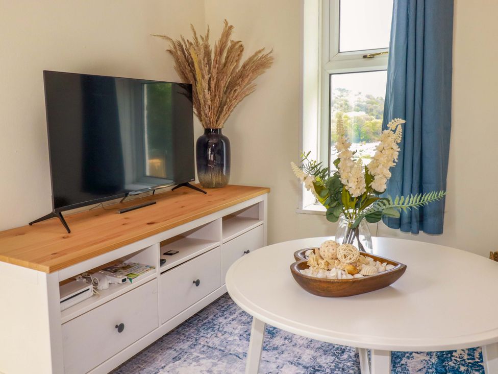 A living room with a television and flowers on a coffee table at Flat 5 in Looe