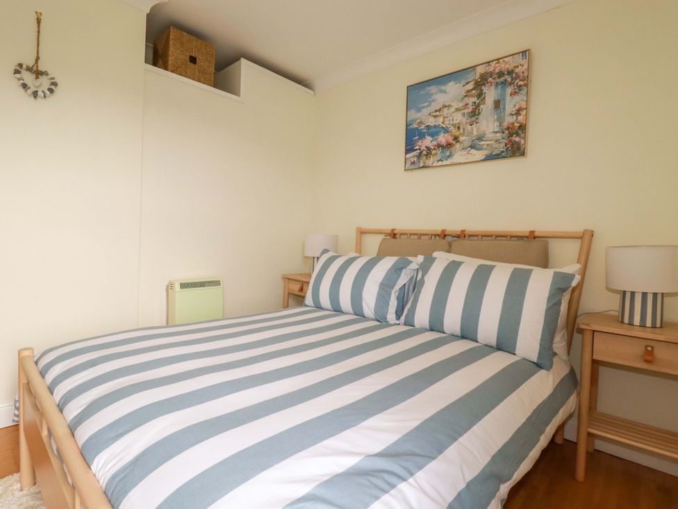 A bedroom with a striped bed and bedside table at Flat 5 in Looe