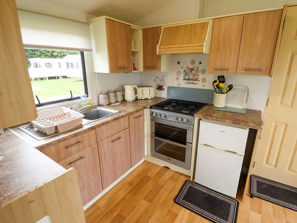 A kitchen with cabinets, stove, and refrigerator at Southview Leisure Park - Firs 83, Skegness