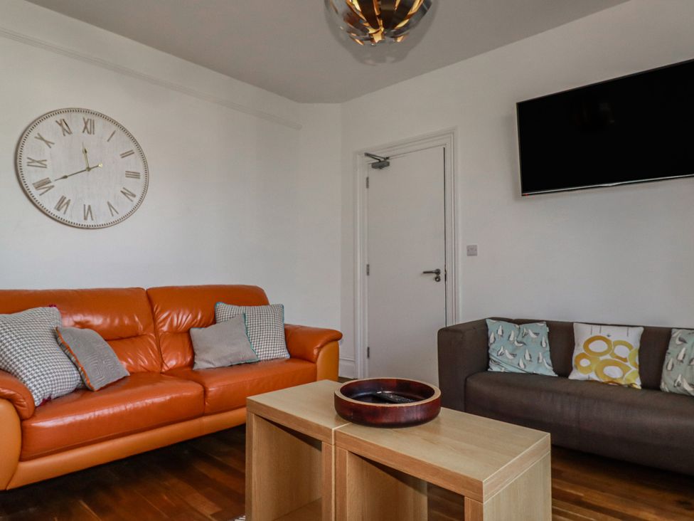 A living room with an orange sofa and a coffee table at Sea View in Newquay