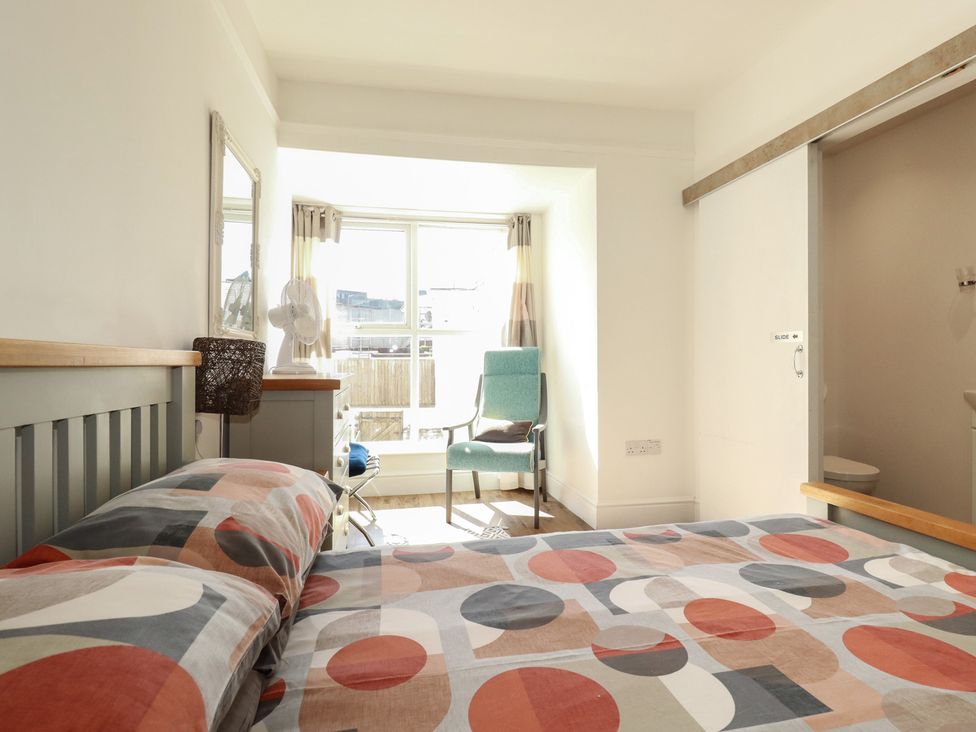 A bedroom with a bed and chair next to a window at Sea View in Newquay