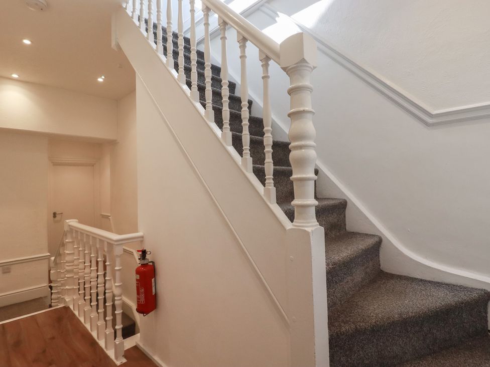 A staircase with a handrail and a fire extinguisher in a hallway at Sea View in Newquay