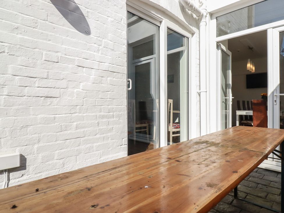 An outdoor area with a wooden table and doors leading to a room at Sea View in Newquay