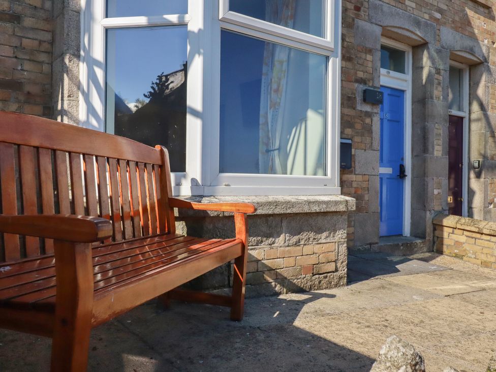 A bench in front of doors and a window at Sea View in Newquay