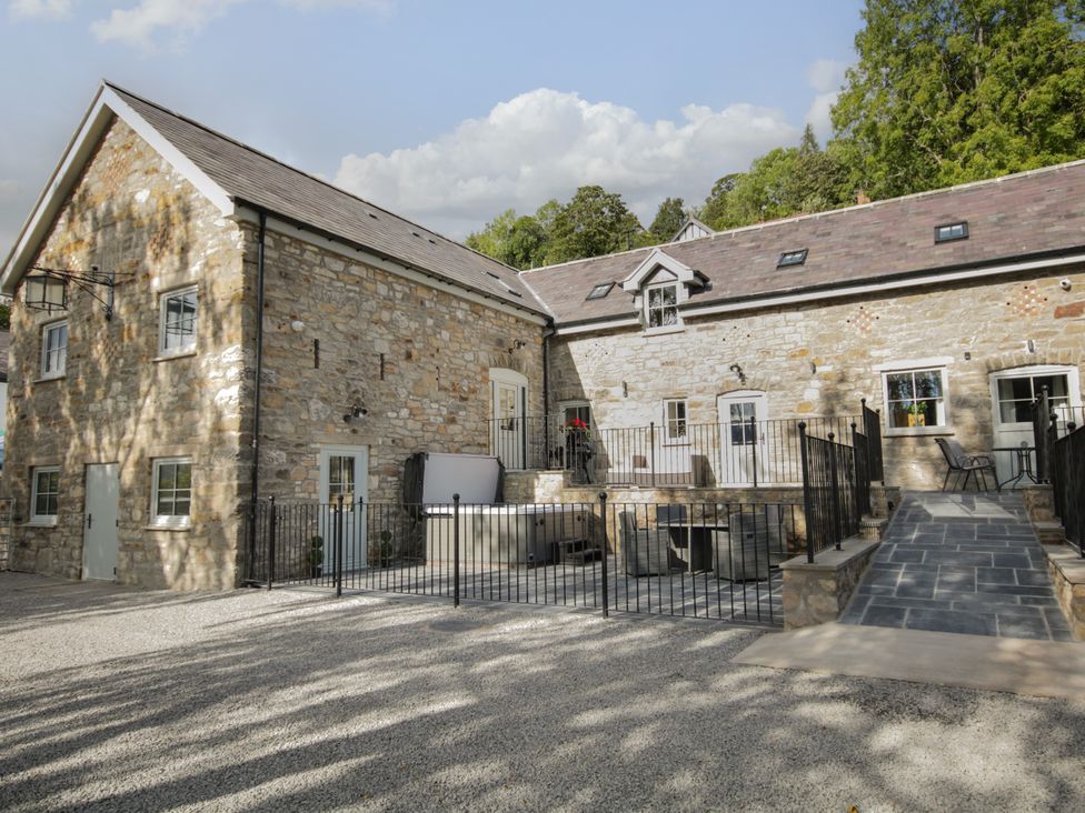 A stone building with windows and a fenced patio area at Sun Trevor Barn 1 Llangollen