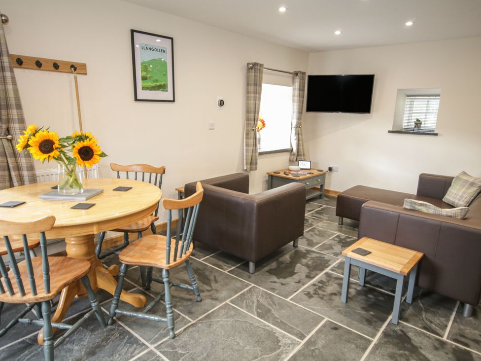 A living room with a table, chairs and a couch at Sun Trevor Barn 1 in Llangollen