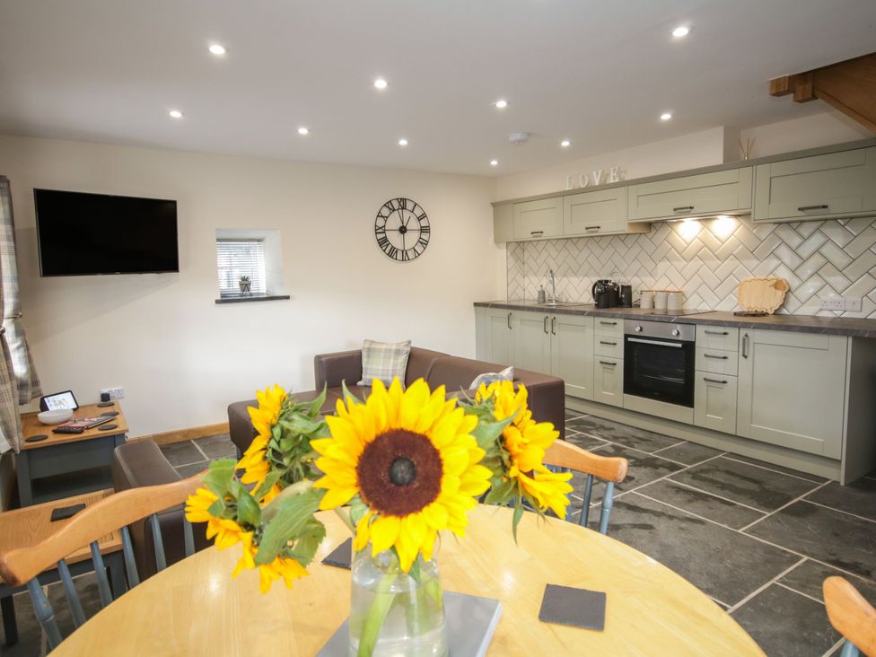 A kitchen with cabinets, a dining table, and sunflowers at Sun Trevor Barn 1 Llangollen