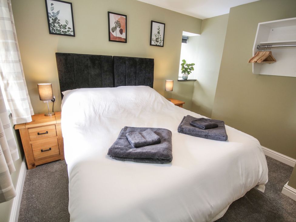 A bedroom with a bed, bedside tables, and wall art at Sun Trevor Barn 1 in Llangollen