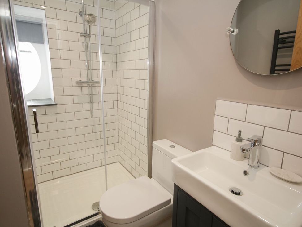 A bathroom with a shower, toilet, and sink at Sun Trevor Barn 1, Llangollen