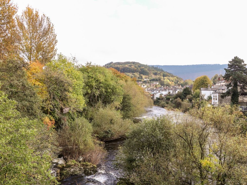 A view of a river surrounded by trees and houses at Sun Trevor Barn 1 in Llangollen