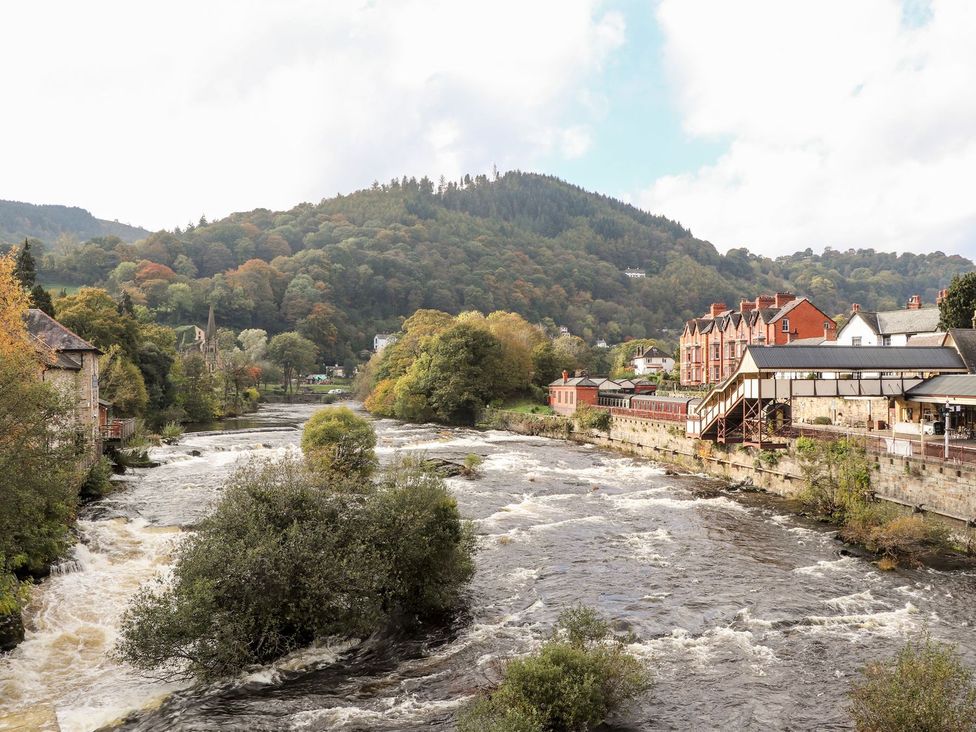 A view of a river with buildings and mountains at Sun Trevor Barn 1 Llangollen
