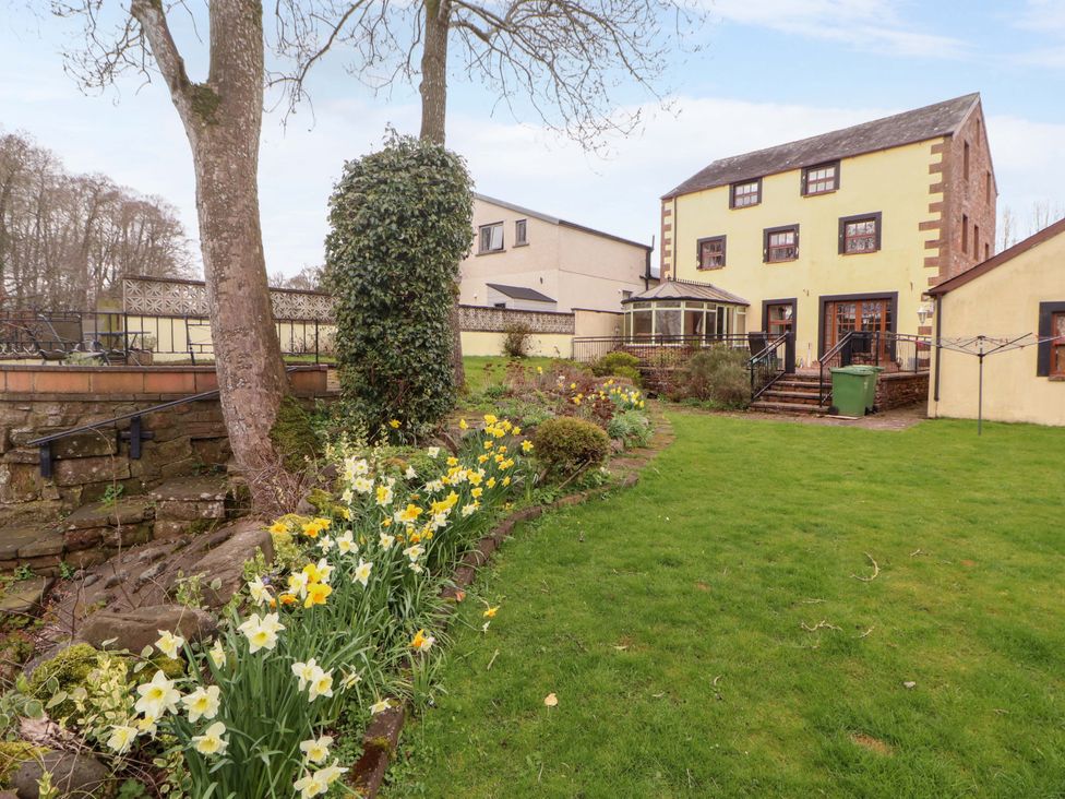 A garden with flowers and a house at High Mill House Penrith