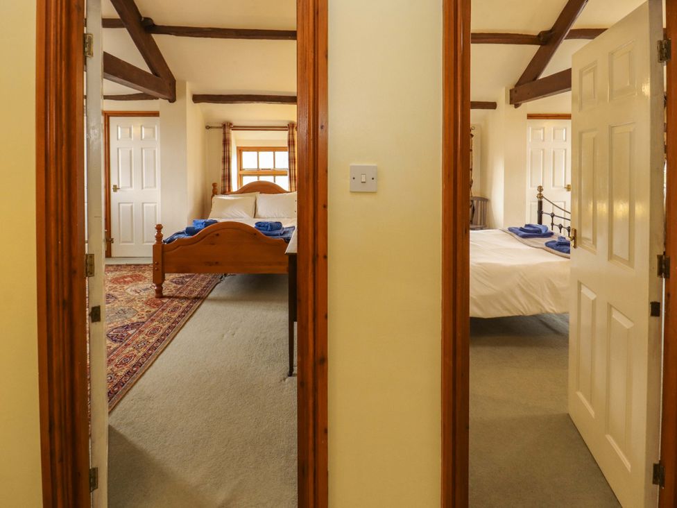 A view into two bedrooms with beds and wooden features at High Mill House in Penrith