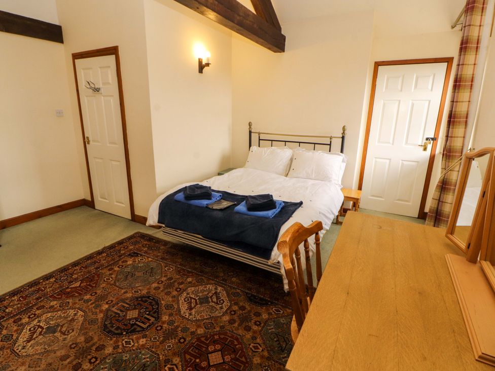 A bedroom with a bed and a table at High Mill House in Penrith