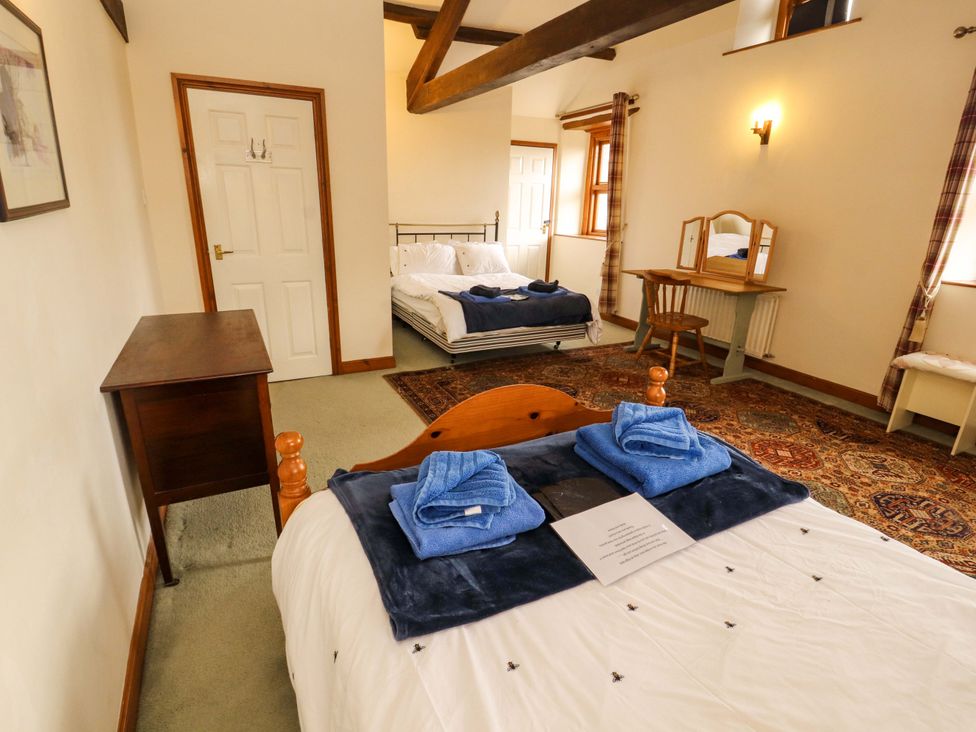 A bedroom with two beds and a wooden table at High Mill House in Penrith