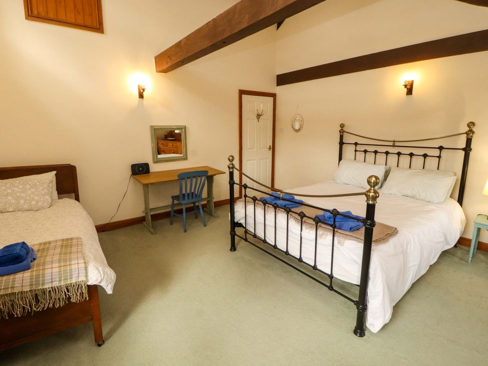 A bedroom with two beds and a desk at High Mill House in Penrith