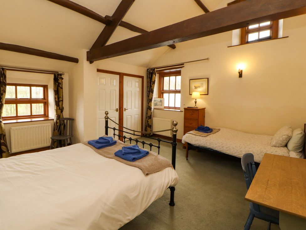 A bedroom with two beds and a desk at High Mill House in Penrith